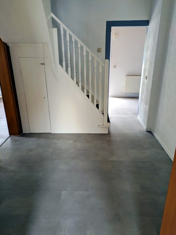 Heller Raum mit Treppe und offener Tür zu einem weiteren Raum.